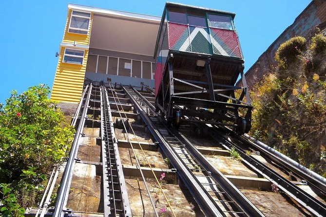 A wooden funicular car on its incline, climbing between the houses of a Valparaiso cerro